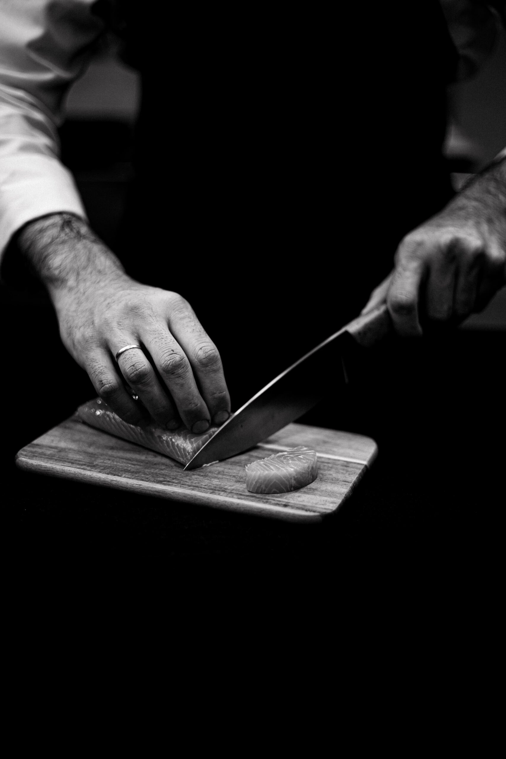 The chef slicing fish with a knife